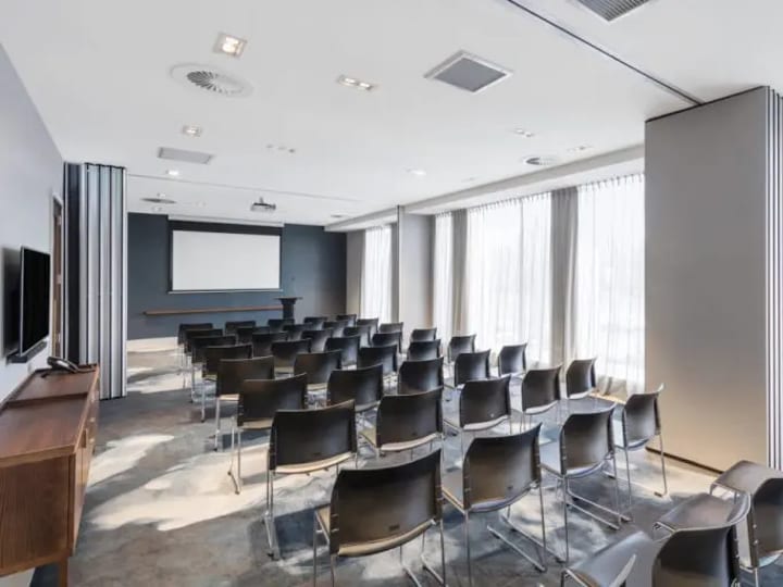 Conference room set with rows of chairs facing a projection screen