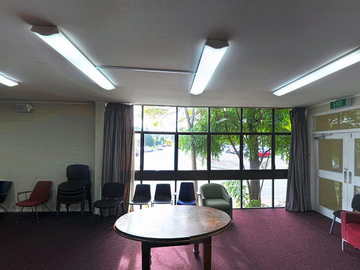 Hall interior with round table, chairs and large windows overlooking trees