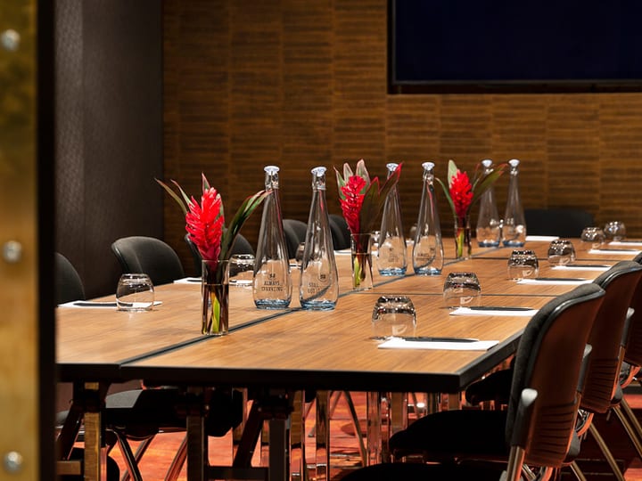Dark timber-slat meeting room with black conference table, large screen, and long windows