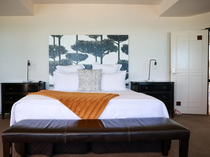 Hotel bedroom with large windows overlooking the ocean and trees