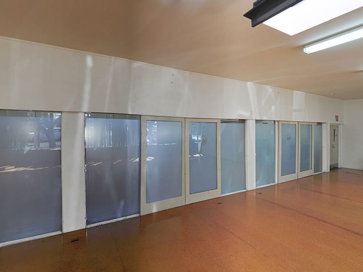 Plain hall room with orange vinyl floor, chairs along walls and windows