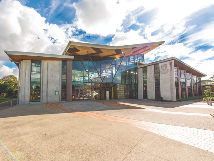 Contemporary building with concrete columns, large glazed facade, and timber canopy entrance