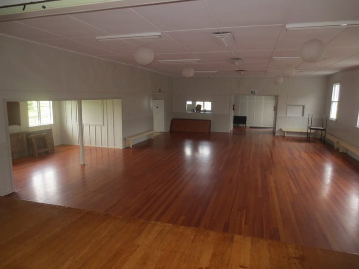 Plain community hall interior with polished timber floor and paper lanterns