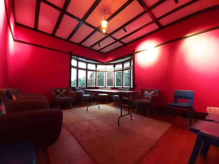 Red-painted lounge room with armchairs and bay window