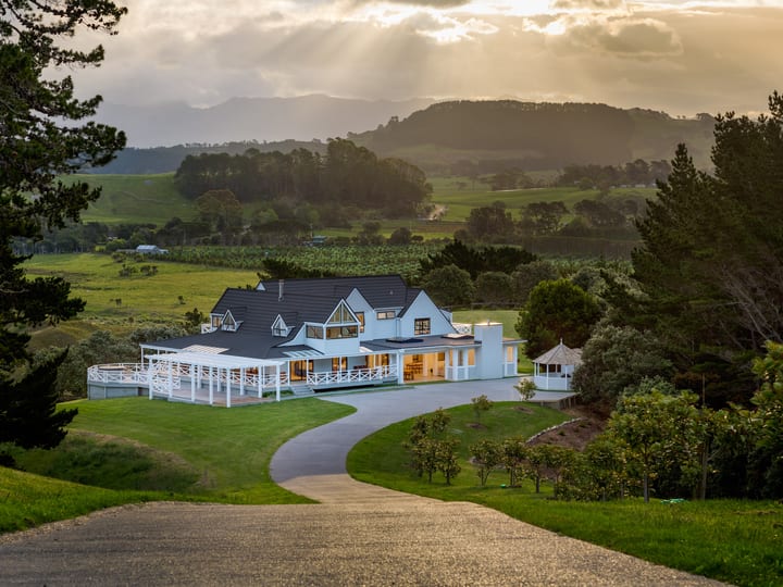 Main building lit at dusk seen from the hilltop driveway with valley and hills behind