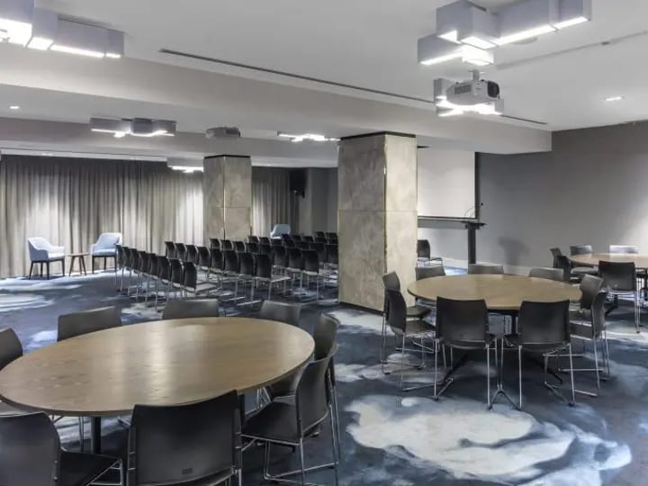 Large conference room with mixed round and straight table layouts, projector