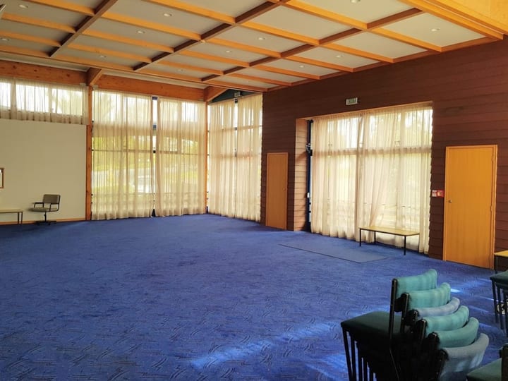 Function room with timber ceiling, blue carpet and large windows along one wall