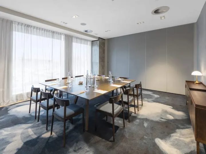 Hotel meeting room with square table configuration, chairs, and large windows