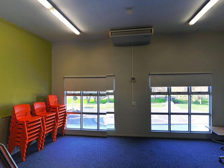 Plain room with dark carpet, whiteboard and table, yellow accent wall visible