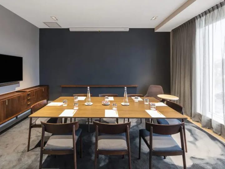Hotel conference room with round tables, chairs, projector screen, and patterned carpet