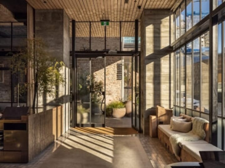 Hotel lobby with concrete walls, timber ceiling, large windows and lounge seating
