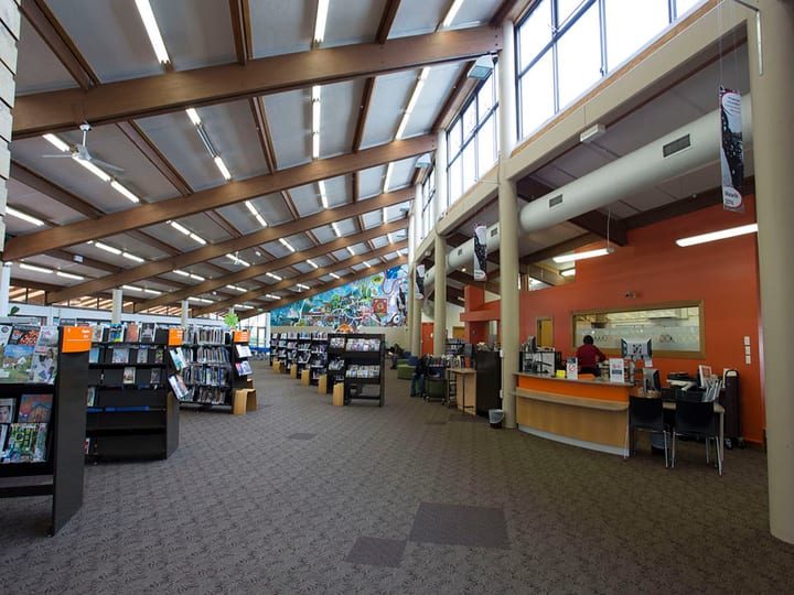 Library interior with high timber-beamed ceiling, book displays, and service counter