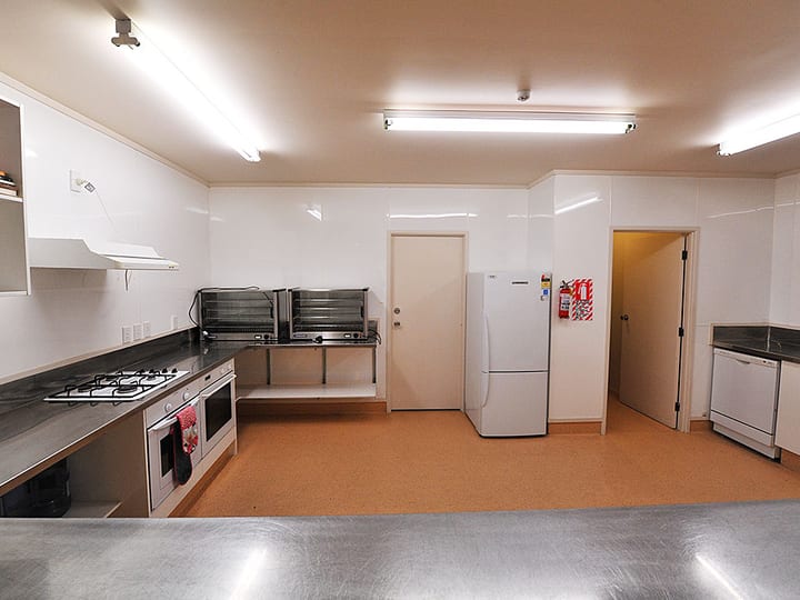 Commercial kitchen with gas hobs, commercial oven, fridge and stainless bench