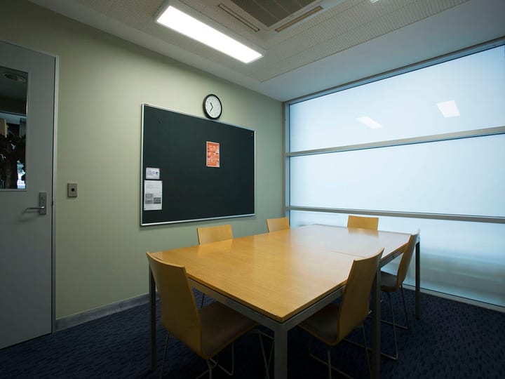 Small meeting room with table, chairs, noticeboard, and frosted window