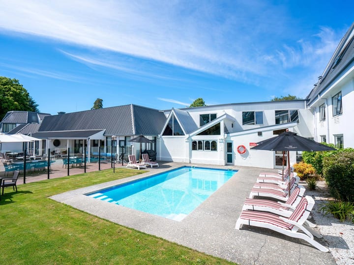 Outdoor swimming pool with sun loungers and white hotel buildings