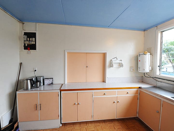 Kitchen with pastel cabinets, bench, kettle, and hot water unit