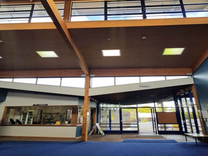 Open foyer interior with timber beams, clerestory windows, and glazed entry wall