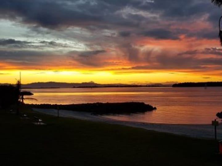 Sunset view over harbour from grounds with lawn and jetty