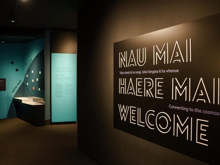 Dark museum entrance corridor with welcome signage and exhibition panels