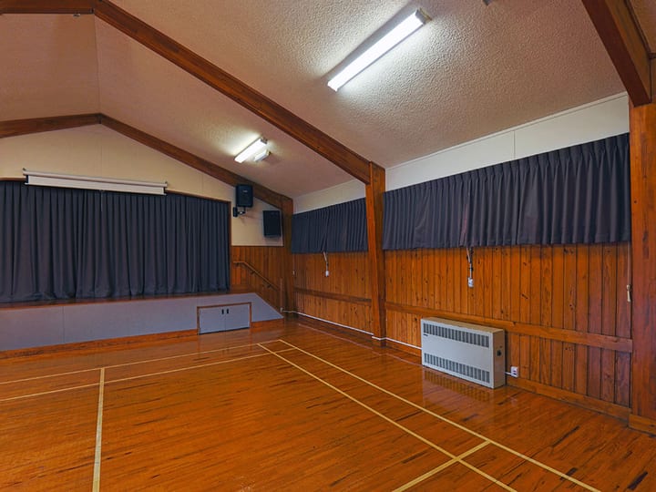 Community hall interior with timber-panelled walls, parquet floor and raised platform