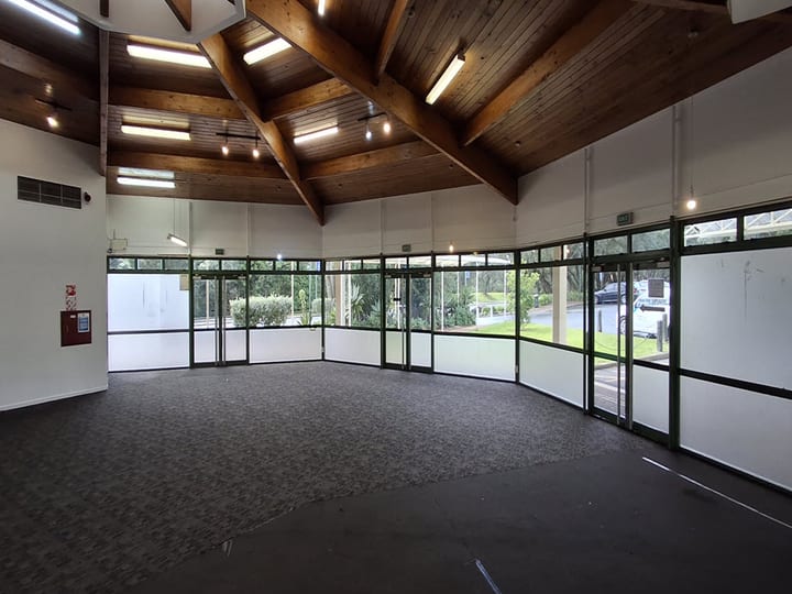 Curved hall with exposed timber roof beams and full-height glazed walls