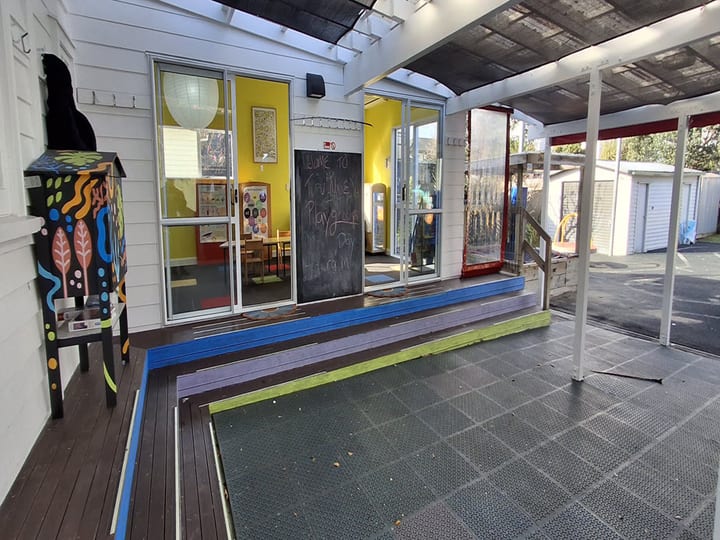 Covered deck area outside colourful playgroup room with ramp and shade cloth