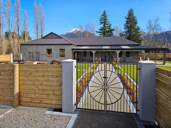 Venue exterior with timber gate featuring wheel motif, lawn, and mountain backdrop
