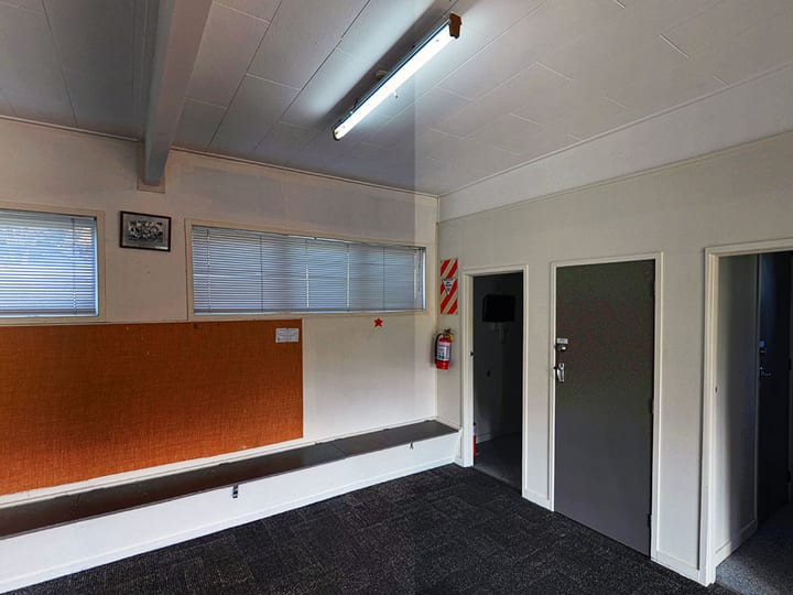 Small plain room with bench seating, carpet, and fluorescent lighting