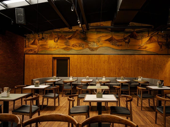 Timber-panelled dining room with painted landscape mural, booth seating and round tables