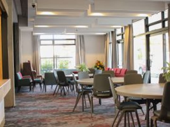 Lounge area with mixed seating, tables, and large windows
