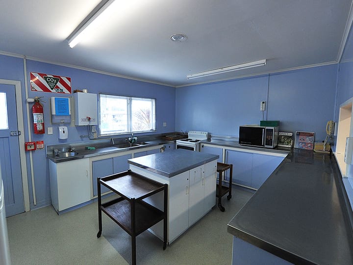 Hall kitchen with blue walls, stainless benches and central preparation table
