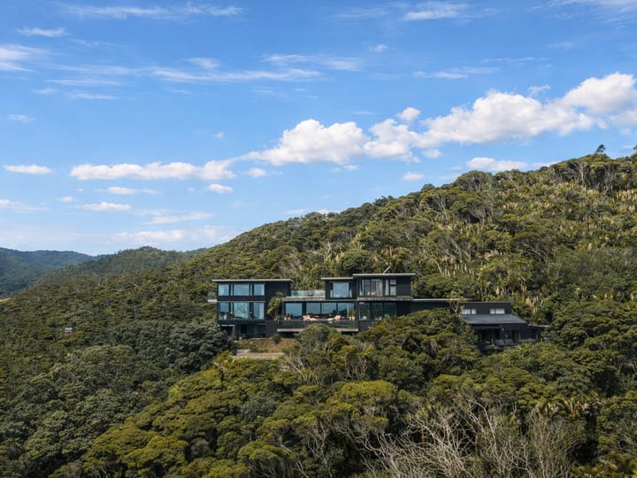 Dark-clad multi-level building set into densely forested hillside