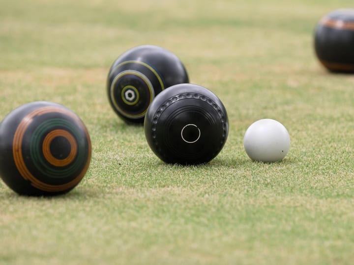 Lawn bowls balls clustered around a jack on a green