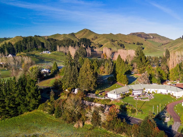 Aerial view of lodge buildings set among trees in a rural valley with hills