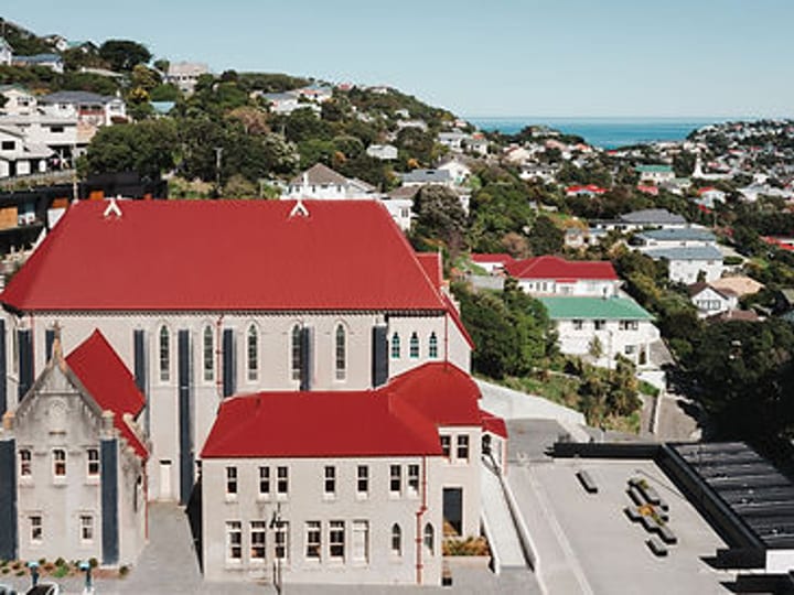 Aerial view of Gothic stone chapel with red roof in a Wellington suburb near the coast