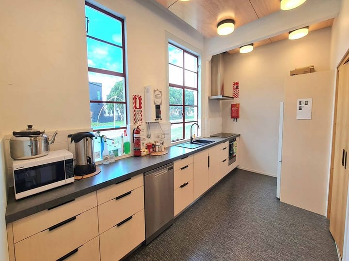 Narrow kitchen with bench, appliances, and tall windows