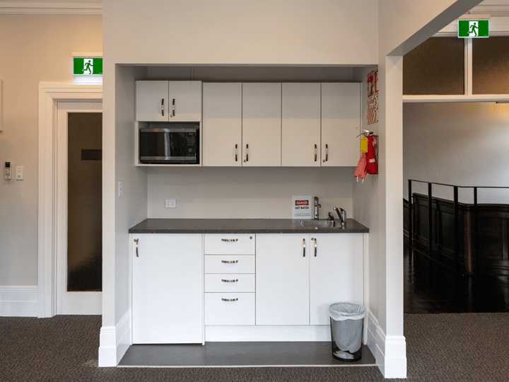 Small servery kitchenette with white cabinets and fire extinguisher