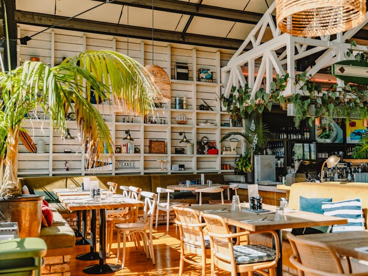 Bright restaurant interior with leather banquette seating and large windows