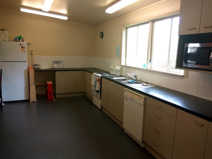 Hall kitchen with stainless benchtops, white cabinets, fridge, and stove