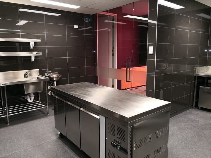 Commercial kitchen with dark tiles, stainless steel bench and equipment