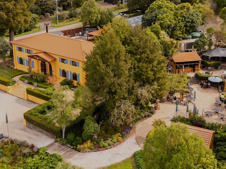 Aerial view of ochre Mediterranean-style winery building amid trees and lawns
