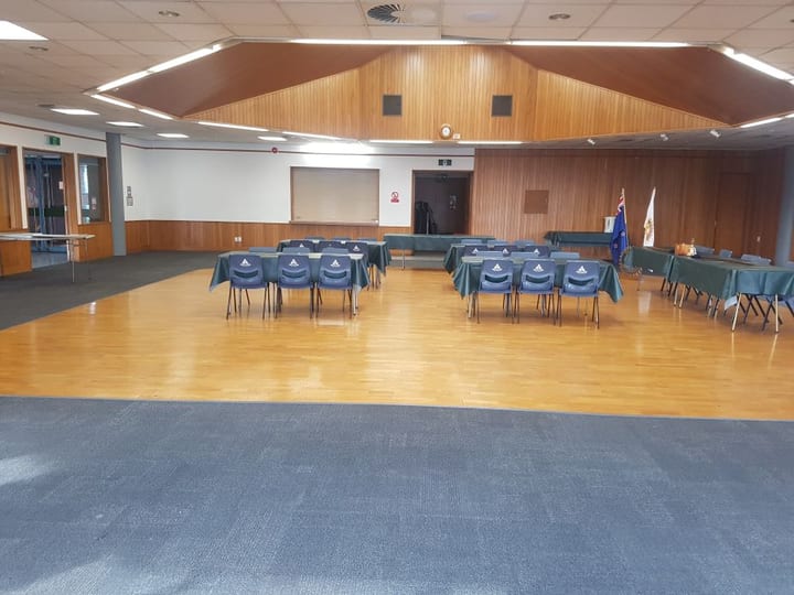 Spacious hall with timber feature wall, polished floor and chairs at tables