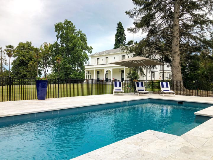 Outdoor pool with loungers and white villa visible in background