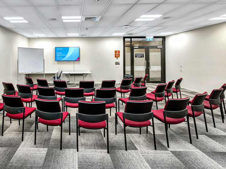 Meeting room with chairs arranged in a horseshoe, whiteboard, and projection screen