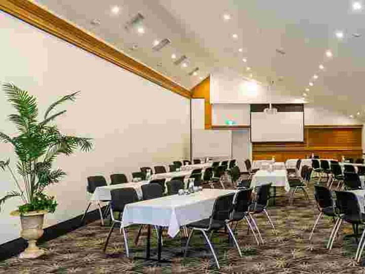 Conference room with clustered round tables, projection screen and gold chandeliers