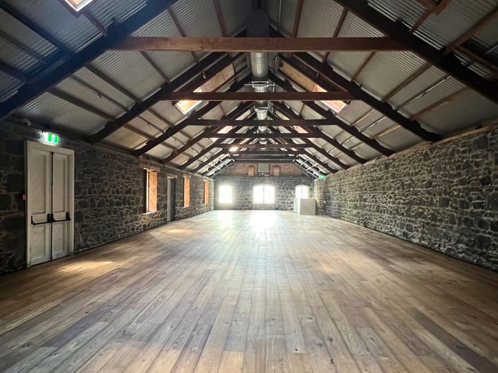 Empty stone-walled barn with exposed rafters and timber floor