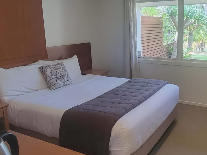 Motel room with double bed, timber furniture, and garden view window