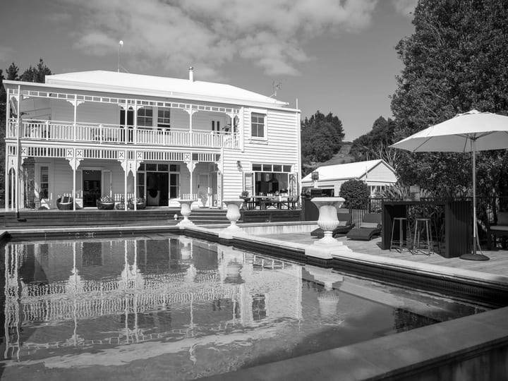 Two-storey white weatherboard villa with wraparound verandahs, a pool terrace and outdoor bar