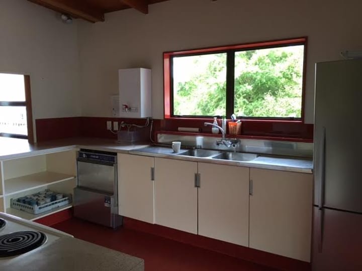 Hall kitchen with red-trimmed cabinetry, stainless sink, commercial dishwasher, and garden window