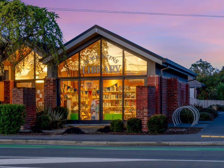 Brick community centre library building lit up at dusk